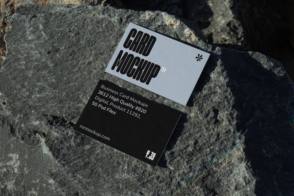 View from above, two outdoor business card mockups with blue and black colors, strong typography design, laying on massive stone.