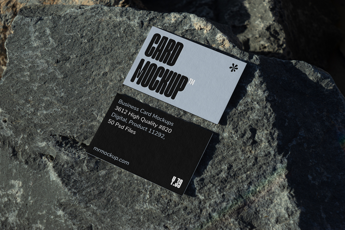 View from above, two outdoor business card mockups with blue and black colors, strong typography design, laying on massive stone.