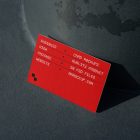 Front view, single outdoor business card mockup with red and white colors, geometric typography design, leans against a pole.