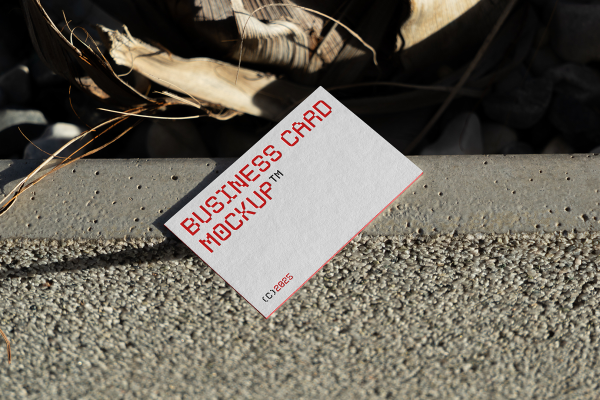 View from above, single outdoor business card mockup with red and black colors, geometric typography design, laying on concrete.