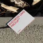 View from above, single outdoor business card mockup with red and black colors, geometric typography design, laying on concrete.