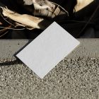 View from above, a single blank outdoor business card mockup laying on concrete.
