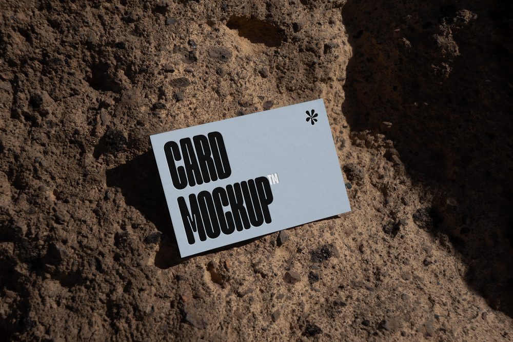 View from above, single outdoor business card mockup with blue and black colors, strong typography design, laying on massive stone.