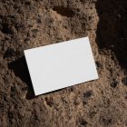 View from above, a single blank outdoor business card mockup laying on massive stone.