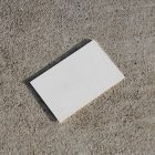 View from above, a single blank outdoor business card mockup laying on the sand background.