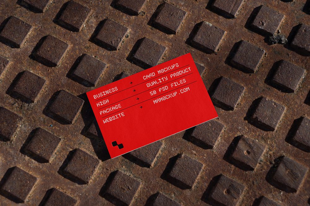 View from above, single outdoor business card mockup with red and white colors, geometric typography design, laying on street manhole.
