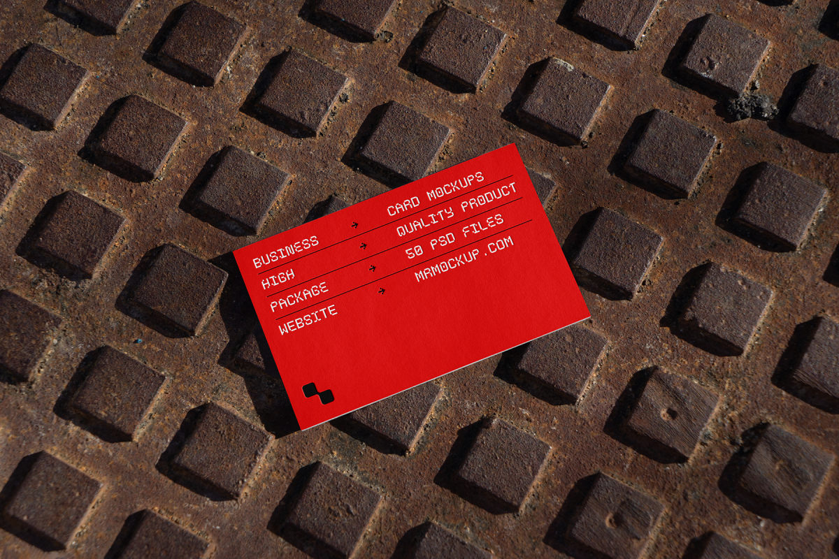 View from above, single outdoor business card mockup with red and white colors, geometric typography design, laying on street manhole.