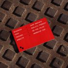 View from above, single outdoor business card mockup with red and white colors, geometric typography design, laying on street manhole.