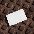 View from above, a single blank outdoor business card mockup laying on a street manhole.