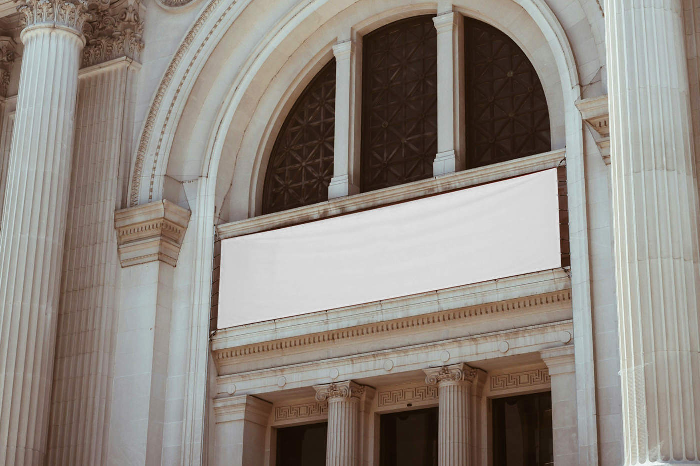 Hanging a white horizontal banner mockup over the entry to the art gallery building.