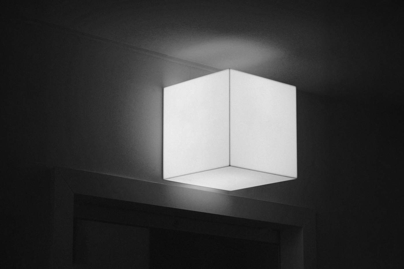 Glowing white square lighting Sign Mockup attached to the wall over the entry to another room.