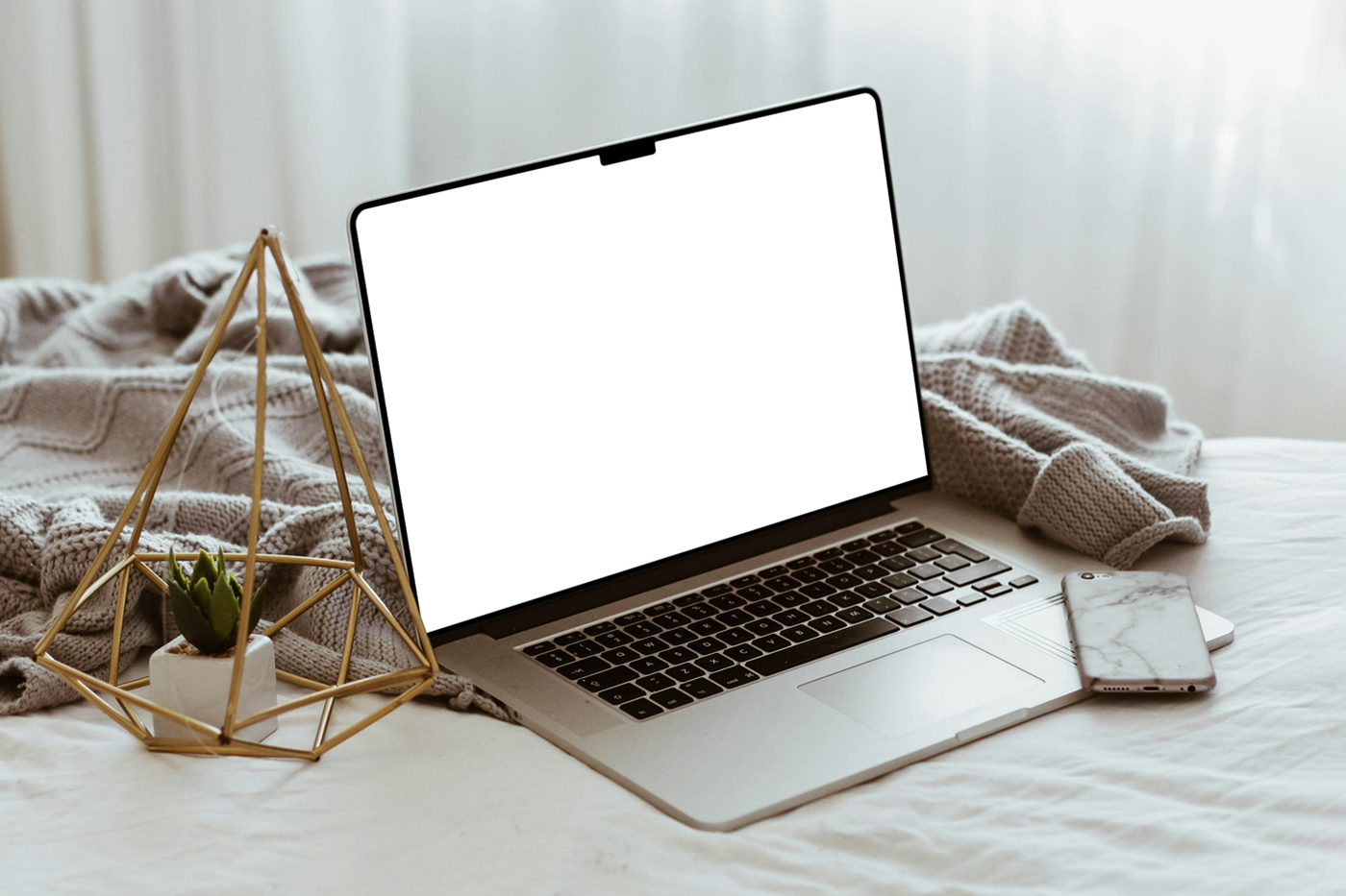 Side view, open silver MacBook Pro Mockup with white screen and decoration accessories laying in the bedroom.