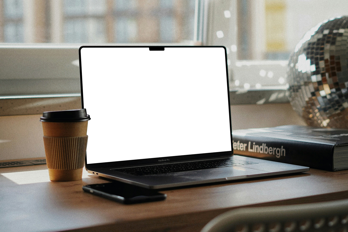 Front view, open silver MacBook Pro Mockup with white screen laying on the wooden desk.
