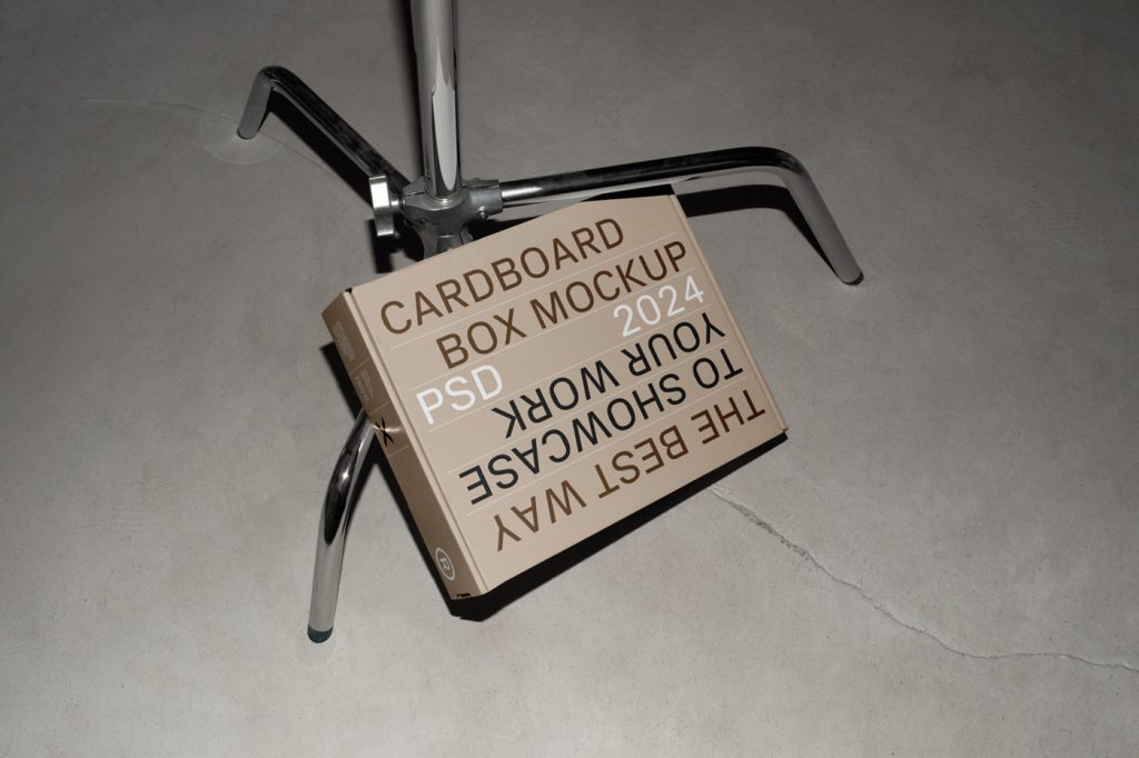 View from above of a craft box mockup with white, brown and black strong typography design based on a metal tripod.