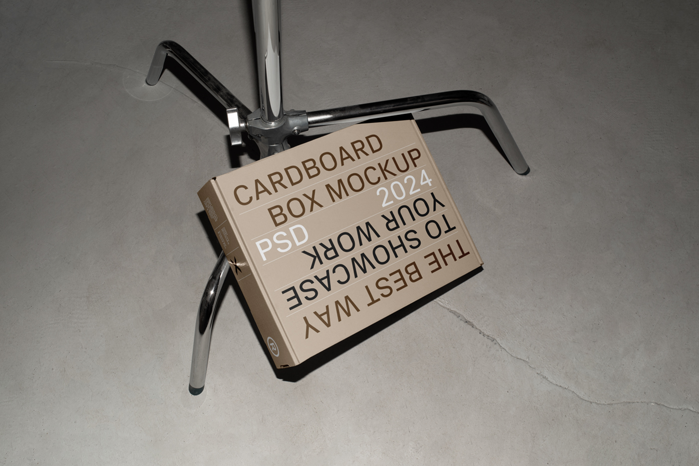 View from above of a craft box mockup with white, brown and black strong typography design based on a metal tripod.