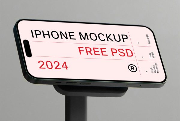 Front view, plugged into the docking station, iPhone 16 Pro Mockup standing on the black desk with a visible dark gray wall behind.
