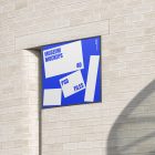 Front view, Square Billboard Mockup with white and blue design attached to the beige brick wall. Scene from our Museum Mockups product.