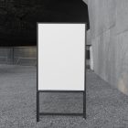 Front view, White Poster Mockup with black metal frame standing on the patio. Scene from our Museum Mockups product.