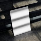 Front view, a white outdoor magazine mockup resists on a metal fence in black color.
