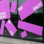 Front view, Transparent Window Mockups with white and pink designs. The windows are built into the building. Scene from our Museum Mockups product.