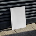 Front view, a white outdoor magazine mockup resists on a metal fence in black color.