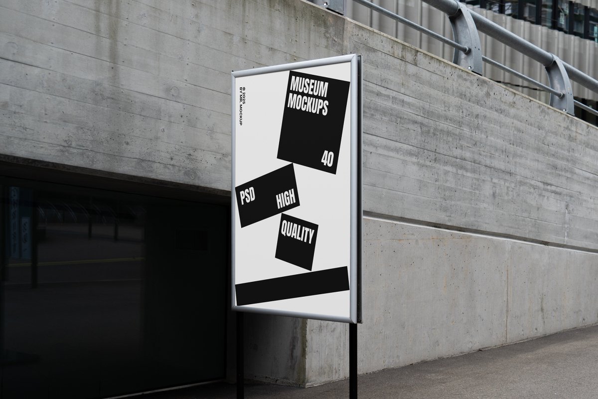Front view, Poster Mockup with white and black design holding on a black metal pole. Standing against the background of a gray concrete wall. Scene from our Museum Mockups product.