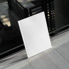 Front view, a white outdoor magazine mockup resists on glass.