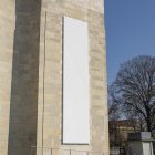 Front view, Vertical White Billboard Mockup attached to the old building against the sky. Scene from our Museum Mockups product.