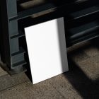 Front view, a white outdoor magazine mockup resists on a metal fence in black color.