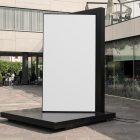 Front view, Vertical White Billboard Mockup attached to the black metal landing. In the background you can see people sitting at tables. Scene from our Museum Mockups product.
