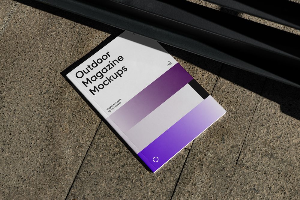 View from above of an Outdoor Magazine Mockup with three gradient shades and strong typography design lying on marble under a metal fence in black color.