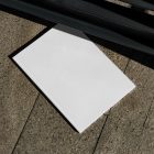 View from above of a white outdoor magazine mockup lying on marble under a metal fence in black color.