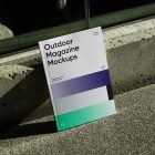 Front View, Outdoor Magazine Mockup with three gradient shades and strong typography design resists on concrete curb.