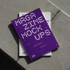 View from above of an Two Outdoor Magazine Mockup with strong purple typography design lying on concrete slabs.