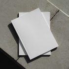 View from above of two white outdoor magazine mockups lying on concrete slabs.