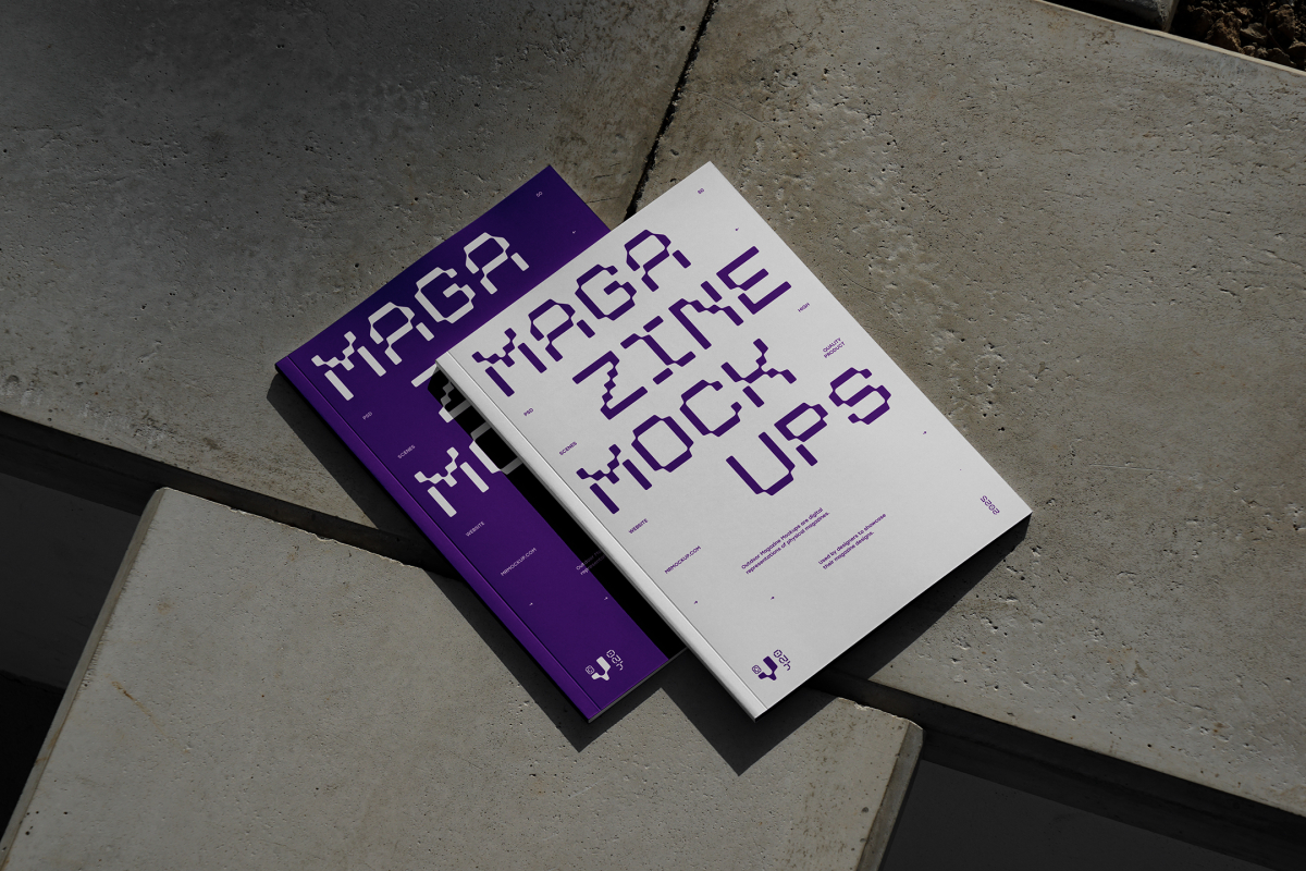 View from above of an Two Outdoor Magazine Mockup with strong purple typography design lying on concrete slabs.