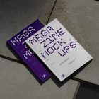 View from above of an Two Outdoor Magazine Mockup with strong purple typography design lying on concrete slabs.