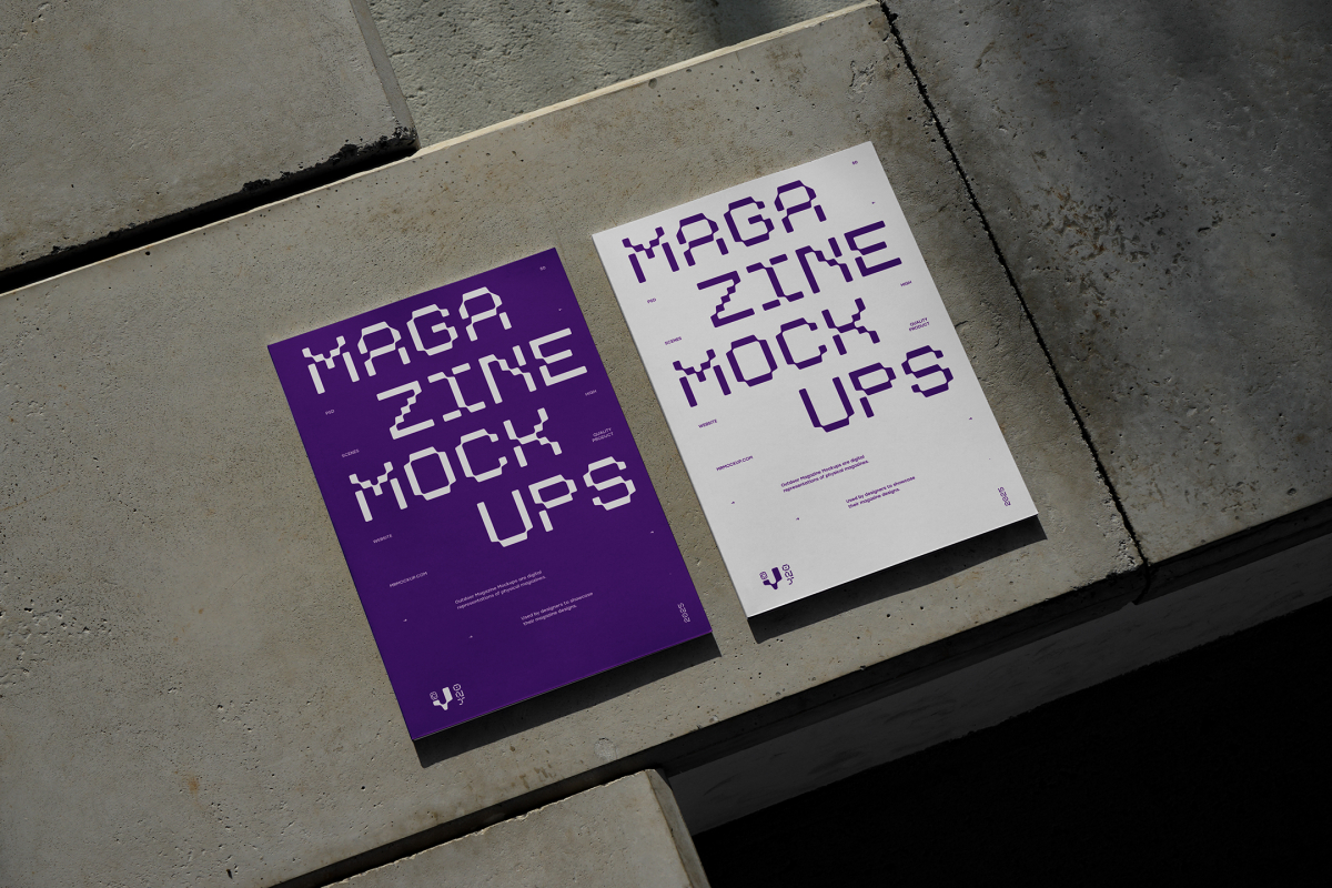View from above of an Two Outdoor Magazine Mockup with strong purple typography design lying on concrete slabs.