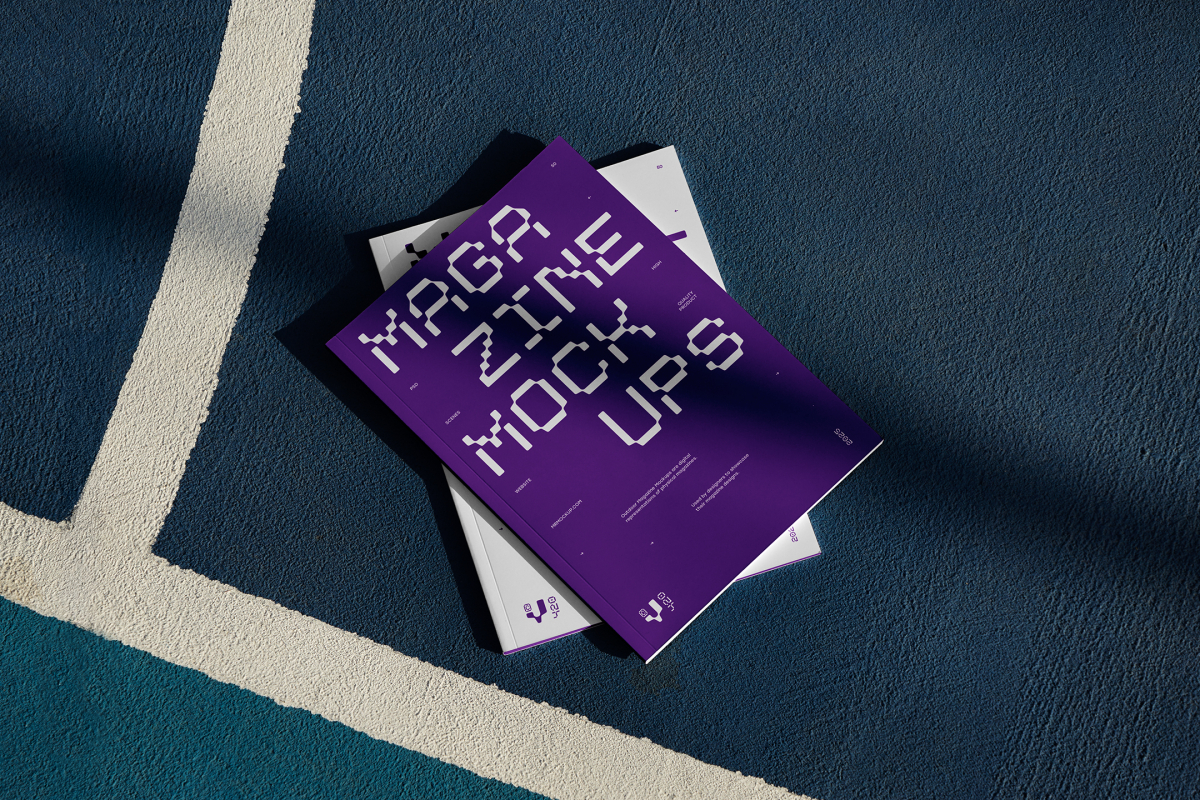 View from above of two outdoor magazine mockups with strong purple typography designs lying on a basketball court.
