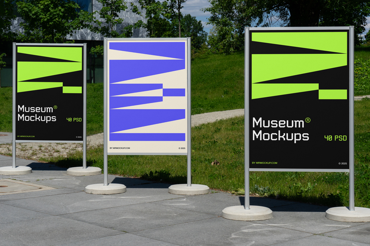 Front view, Three Poster Mockups with white, black, beige, and purple geometric designs standing on the side wall in front of the city park. Scene from our Museum Mockups product.