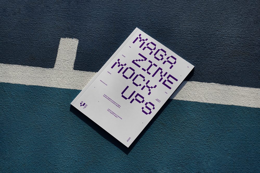 View from above of outdoor magazine mockups with strong purple typography design lying on a basketball court.