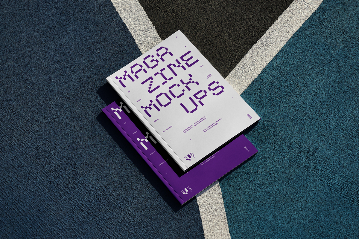 View from above of two outdoor magazine mockups with strong purple typography designs lying on a basketball court.