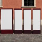Front view, Four White Vertical Poster Mockups standing in front of the old building. Scene from our Museum Mockups product.