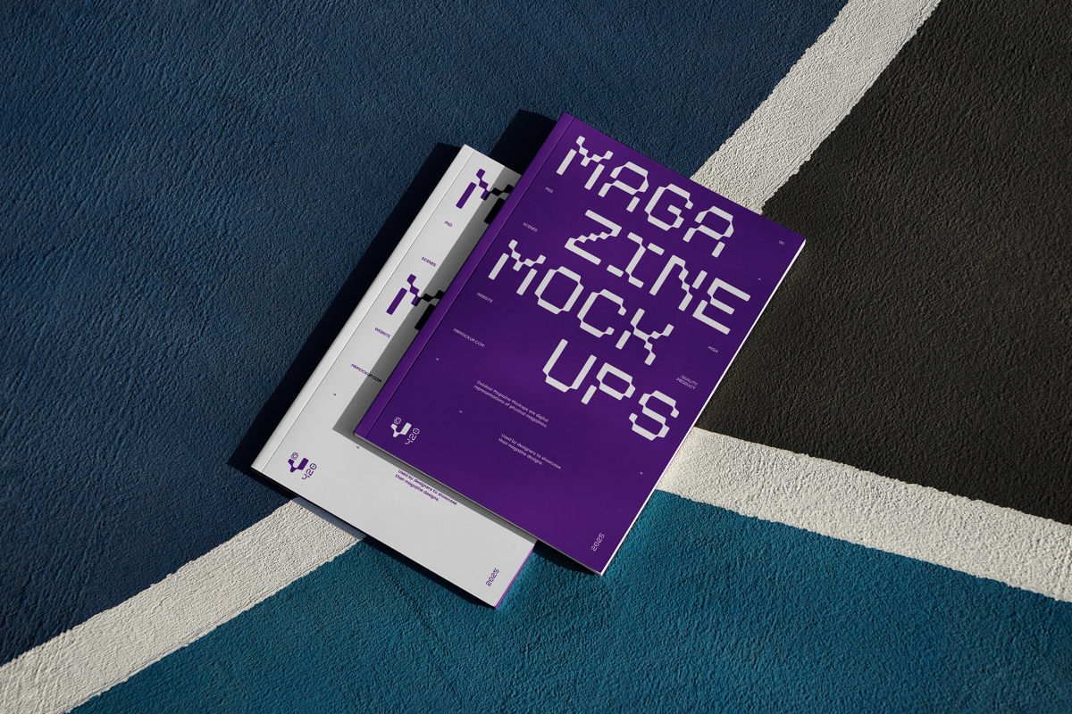 View from above of two outdoor magazine mockups with strong purple typography designs lying on a basketball court.