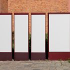 Front view, Four White Vertical Poster Mockups standing in front of the old building. Scene from our Museum Mockups product.