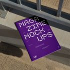 View from above of outdoor magazine mockups with strong purple typography design lying on concrete under a metal fence in silver color.