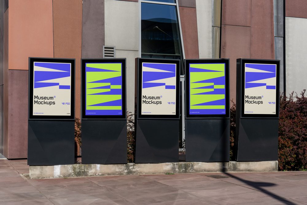 Front view, Five Poster Mockups with purple, black, beige, and neon green geometric designs standing in front of the modern architecture building. Scene from our Museum Mockups product.