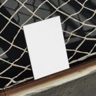Front view, of a white outdoor magazine mockup resists on string net.