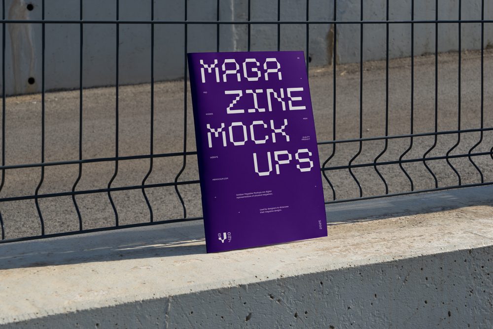 Front view, of outdoor magazine mockups with strong purple typography design resists on metal net fence in black color.