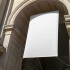 View from below, White Hanging Banner Mockup holding on to ropes attached to the building. Scene from our Museum Mockups product.